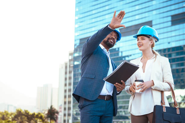 istock Colleges in hard hats discussing their new building plan 2158227021
