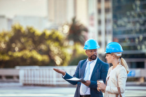istock Colleges in hard hats discussing their new building plan 2158227113
