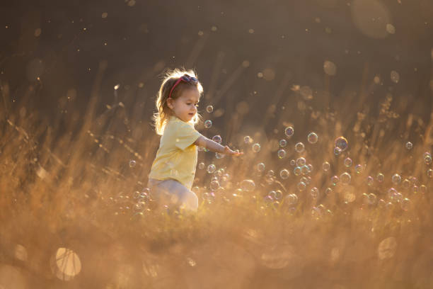 Full length of little girl playing with bubbles outdoors