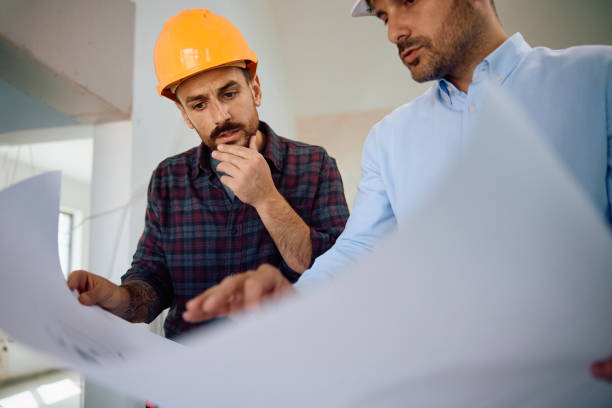 istock Manual worker and construction site engineer going through hosing plans at renovating home. 2158230509