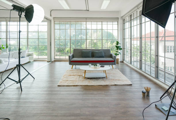 istock A bright, modern photo studio with large windows, cozy sofa, coffee table, and professional lighting equipment. 2158232217