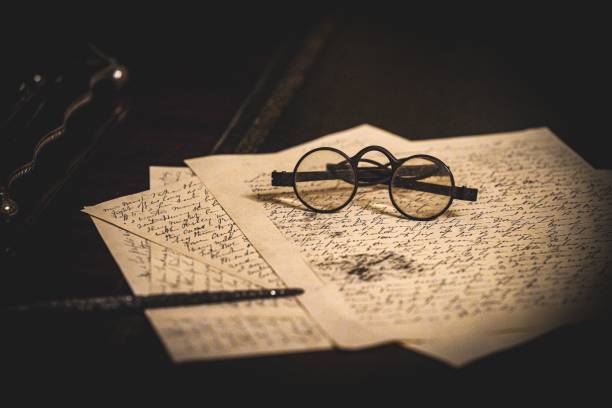 istock Old historic antique eyeglasses on a stack of papers with cursive writing on them and a pen 2158233082