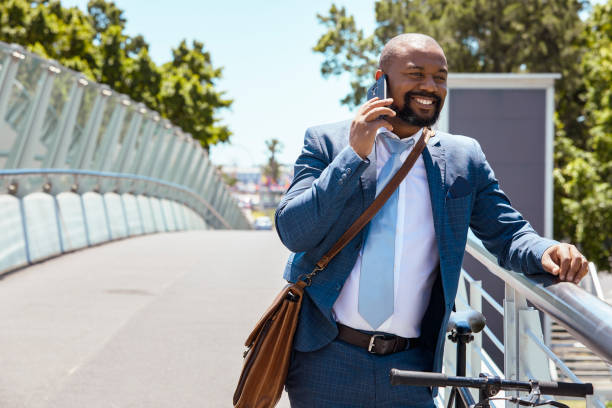 istock A businessman standing with his bicycle on a bridge talking on his phone on a beautiful summer day 2158233681