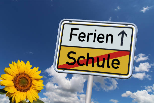 Symbol image: German town exit sign with the words Schule/Ferien (school/holiday) against a blue sky