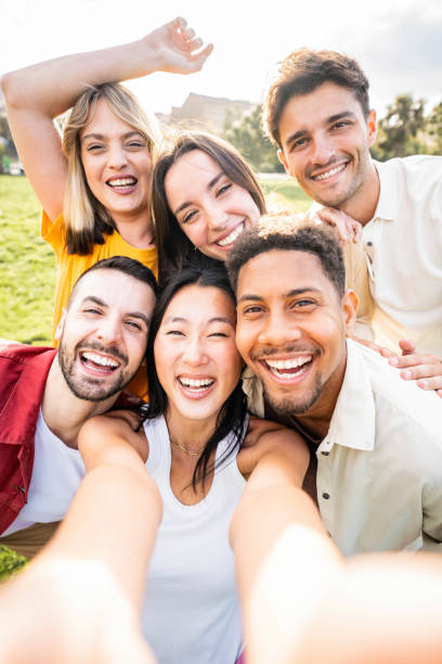 istock Multiracial young people taking selfie pic with smart mobile phone device - Vertical photo of happy friends smiling at camera - Life style concept with guys and girls hanging out on summer day 2158234024