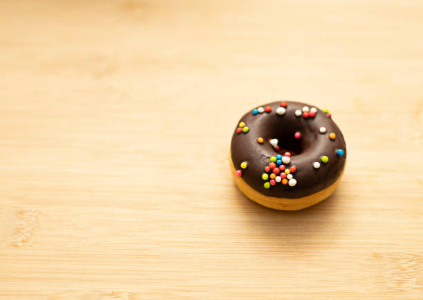 Chocolate faced donuts placed on wooden background with copy space.