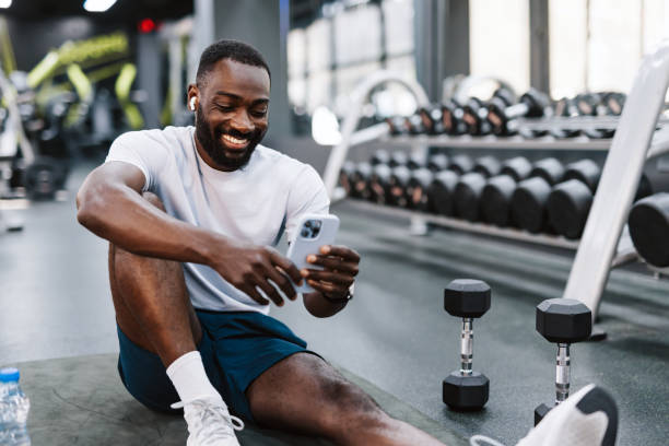 istock Man on gym floor with smartphone 2158235712