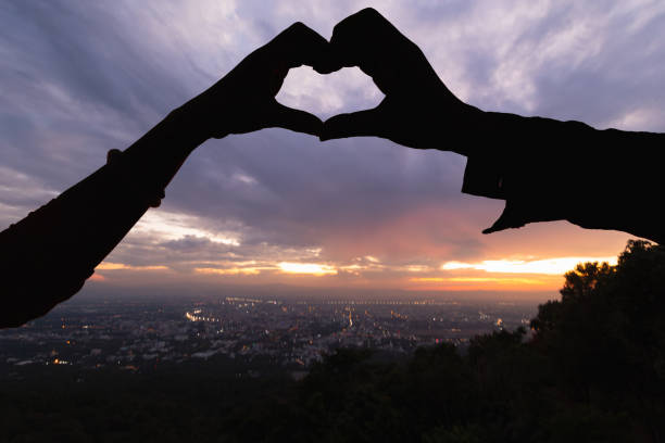 istock Silhouette couple hands raised up make heart shape on beautiful evening landscape background. concept making hand shaped heart symbol express love friendship and kindness towards lovers and friends. 2158238708