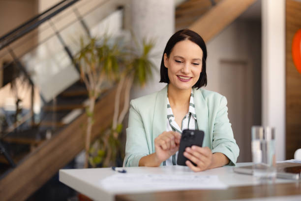 istock Smiling businesswoman using phone in office 2158238755
