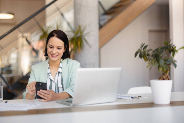 istock Smiling businesswoman using phone in office 2158238758