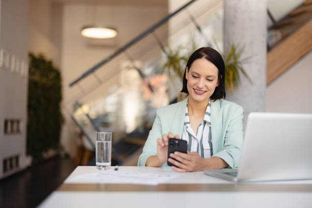 istock Smiling businesswoman using phone in office 2158238761