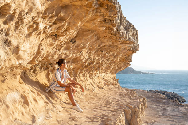 istock Serenity at Sunset: Man Contemplating by Ocean Rock 2158239478