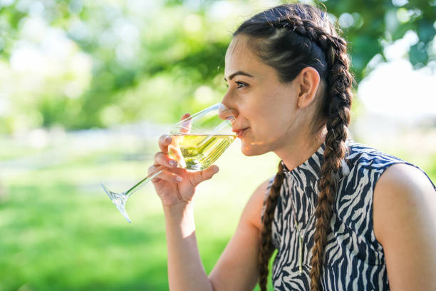 istock woman sitting on a bench outdoors, drinking white wine. 2158241431