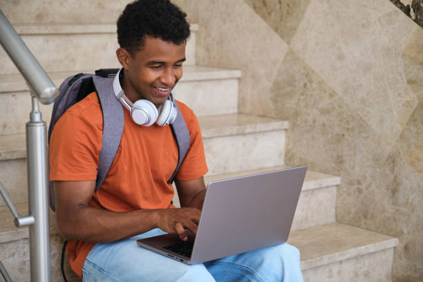istock A young student man is sitting on a staircase with a laptop in front of him 2158241703