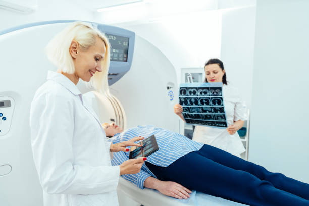 istock Doctor examining X-ray images on display in MRI control room while in background nurse preparing the patient for examination test. 2158241756