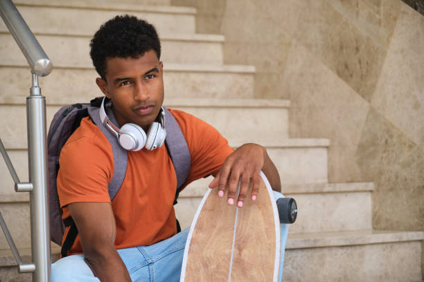 istock A young student man sits on a staircase with a skateboard in his hand 2158241894