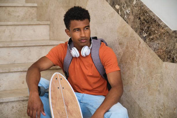 istock A young student man sits on a staircase with a skateboard in his hand 2158242080