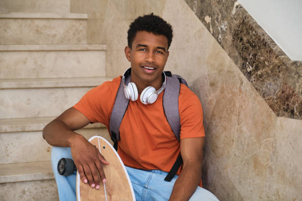 istock A young student man is sitting on a staircase with a skateboard, smiling 2158242128
