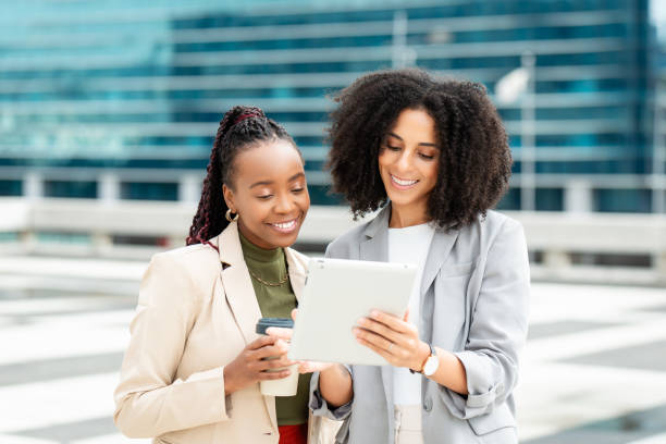 istock Two Businesswomen Collaborating Outdoors on Digital Tablet During Work Meeting 2158244572