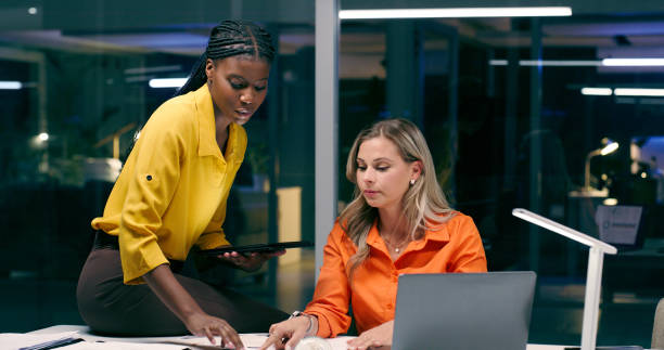 istock Overtime, team and women in office with documents, talking and discussion at night. Teamwork, late work and female partners in boardroom for strategy, corporate project and meeting with laptop 2158245446