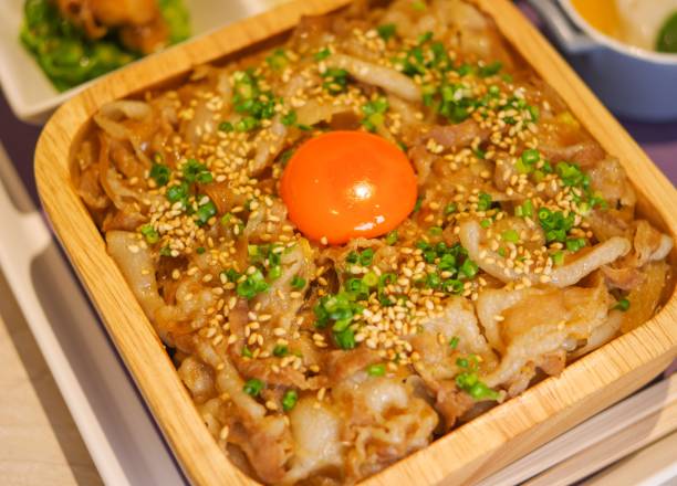 istock Fried beef bento gyudon rice bowl lunchbox don with raw egg close up view 2158246564