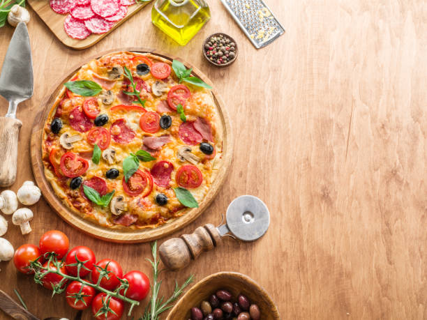 istock Pizza and ingredients are  on wooden table on left side. On right side is empty copy space. Top view. 2158247558