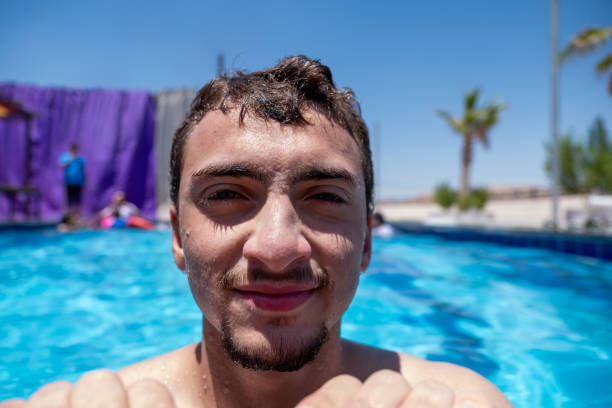 istock A man in a pool, resting his chin on the edge while smiling at the camera. The scene is bright and sunny 2158248331