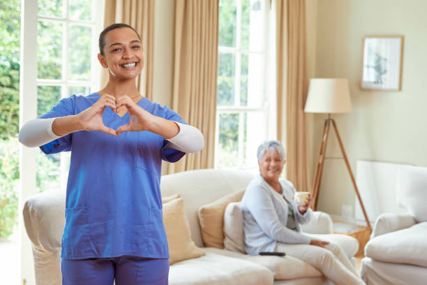 istock Nurse standing in patients living room making a heart shape with her hands 2158251026