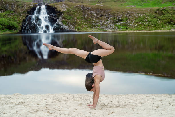 a fitness instructor shows how to correctly perform stretching exercises on the sandy shore of the lake. Workout at nature