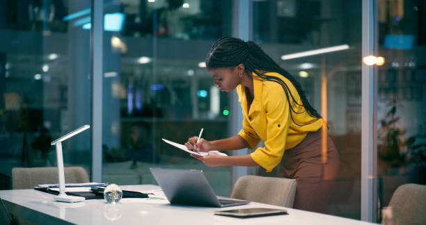 istock Night, business and black woman with documents, planning and brainstorming for deadline, project and article. African person, employee and journalist with laptop, paperwork and evening with research 2158254145