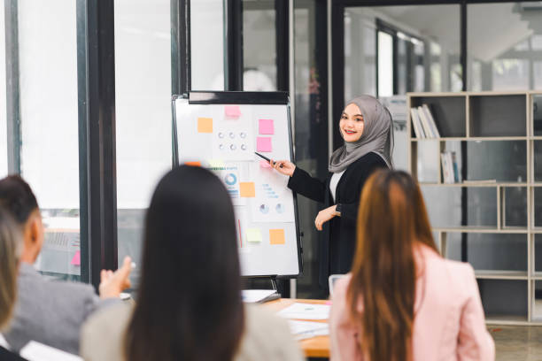istock Confident businesswoman in hijab leading team presentation with data charts and graphs, engaging colleagues in modern office. 2158254882