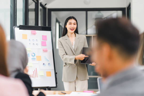 istock Smiling businesswoman leading an interactive presentation with her team, discussing data charts and graphs in modern office. 2158254883
