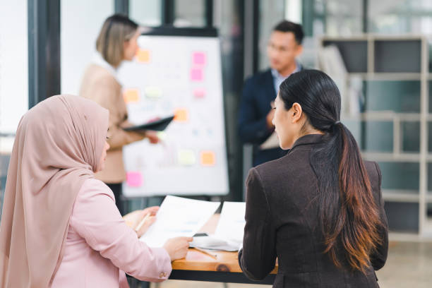 istock Diverse business team analyzing data and discussing strategies during an office meeting, using documents and a laptop. 2158254952