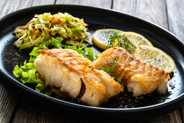 istock Fried codfish fillet and cabbage salad served on wooden table 2158254993