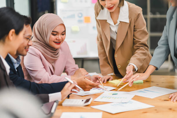 istock Diverse business team analyzing data and discussing strategies during an office meeting, using documents and a laptop. 2158255021