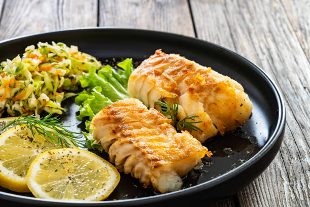 istock Fried codfish fillet and cabbage salad served on wooden table 2158255027