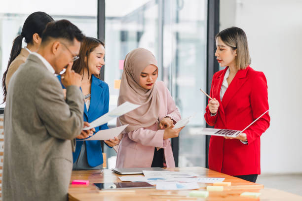 istock Diverse business team analyzing data and discussing strategies during an office meeting, using documents and a laptop. 2158255098