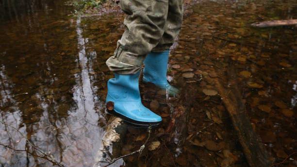 istock Feet in rubber boots on a forest, rural road, hiking through the forest. 2158257394