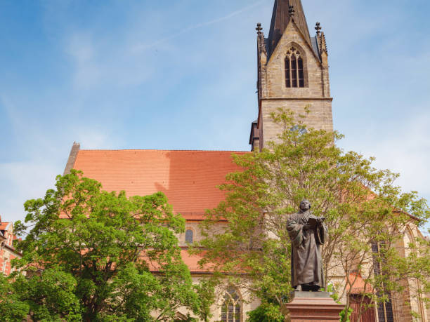 Erfurt, Germany - May 21, 2023: Monument to Martin Luther on Anger Square in Erfurt, Thuringia with Evangelical Church St. Gregor on backdrop