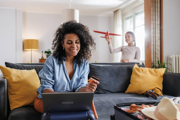 istock A mother is using a laptop and credit card to book flight tickets while her daughter is playing 2158258939