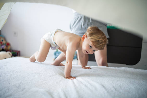 Happy mother and son playing on the bed under the sheets.They are having fun with the bedding.