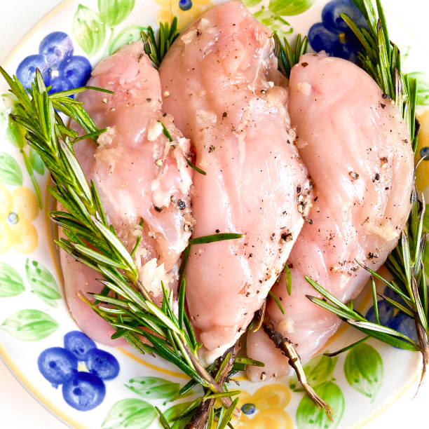High angle view of raw chicken breast with rosemary sprigs to be cooked in oven at home for lunch