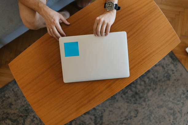 istock Person closing laptop on wooden table 2158268959