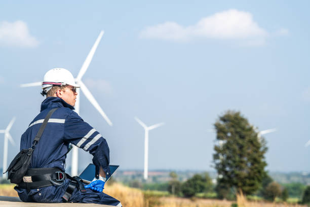 istock A wind energy technician with a laptop analyzes the efficiency of turbines on a clear day. 2158270232