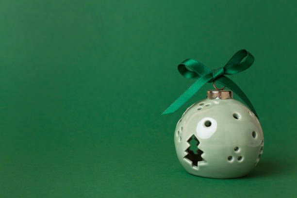 Lamp in Christmas bauble shape on color background