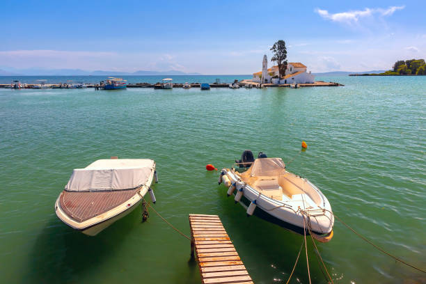 Pontikonisi Island in Corfu, Greece, seen from the sea with boats in foreground