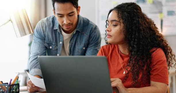 istock People, creative and business documents with laptop, partners and planning discussion for small agency. Talking, contract and sales review or brainstorming project, collaboration and work meeting 2158279963