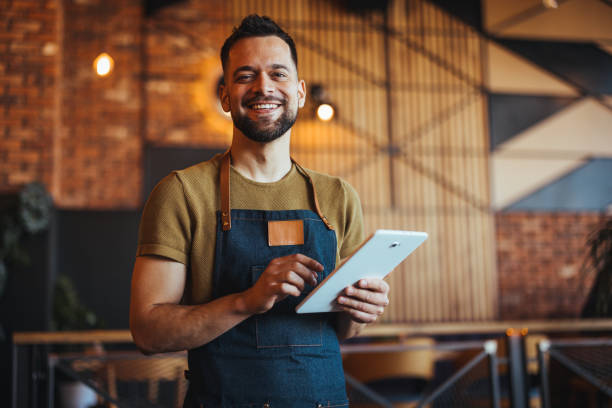 Smiling Caucasian Waiter With Tablet in Modern Eatery