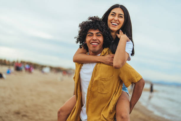 istock Joyful Hispanic Couple Enjoying Piggyback Ride on Beach 2158285303