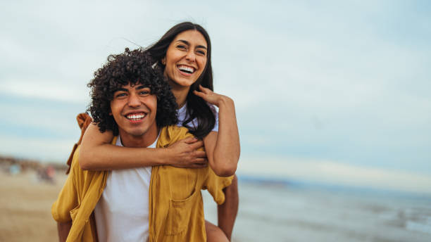 istock Joyful Hispanic Couple Enjoying Piggyback Ride on Beach 2158285321